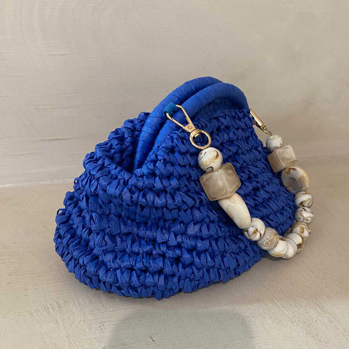 Clutch in rafia all’uncinetto blu con manico in pietra naturale
